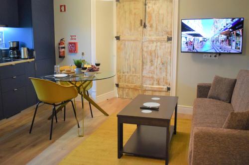 a living room with a table and a couch and a tv at Apartamentos Colmeia in Lisbon