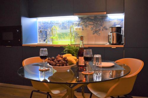 a glass table with a bowl of fruit and wine glasses at Apartamentos Colmeia in Lisbon