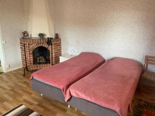 um quarto com lareira e uma cama com cobertor vermelho em Stavred-gården em Bjärtrå