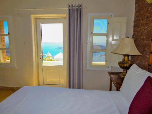 a bedroom with a bed and a window with the ocean at Le Petit Greek in Fira