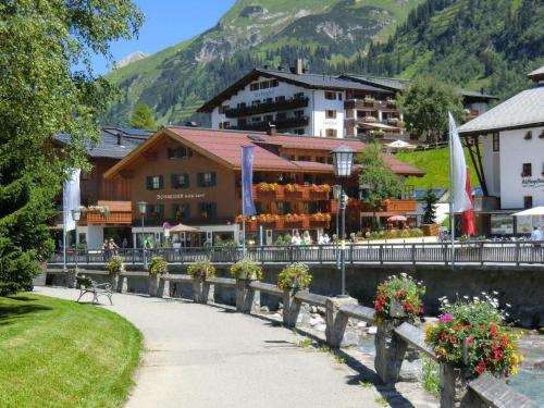 une passerelle devant un bâtiment fleuri dans l'établissement Hotel Garni Schneider, à Lech am Arlberg