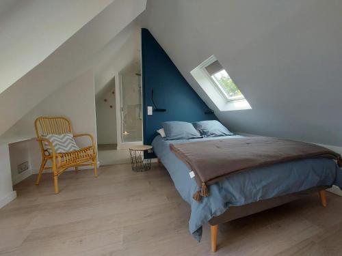 a bedroom with a bed with a blue wall and a chair at Havre de paix et jardin tropical. Chambre privée in Le Rheu