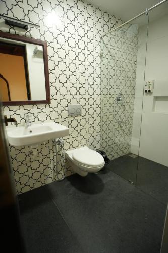 ein Badezimmer mit einem WC, einem Waschbecken und einem Spiegel in der Unterkunft THE SUNSET BAY in Fort Kochi