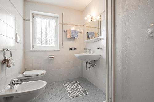 a white bathroom with a sink and a toilet at Ciüf de Munt in Badia
