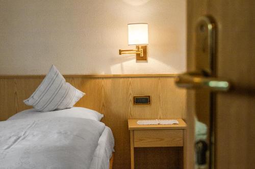 a hotel room with a bed and a lamp on the wall at Ciüf de Munt in Badia