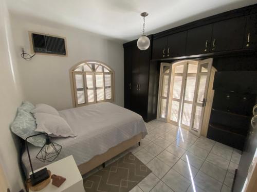 a bedroom with a bed and a table and two windows at Suíte Residencial320 - Timbó in Timbó