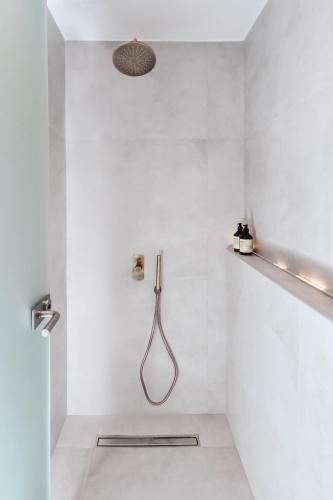 a white bathroom with a shower with a hose at Ikaros Suites in Amoudara Herakliou