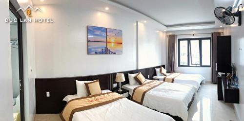河江的住宿－Đức Lan Hotel，酒店客房设有三张床,墙上挂有绘画作品