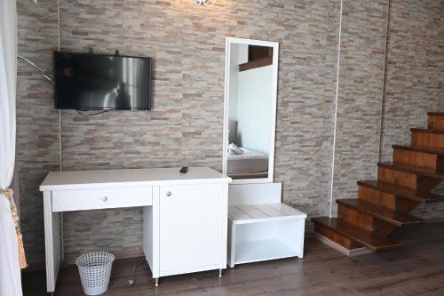 a white dressing table with a tv on a brick wall at Hotel Onufri in Golem