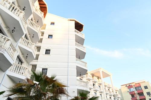 a white building with palm trees in front of it at Hotel Onufri in Golem