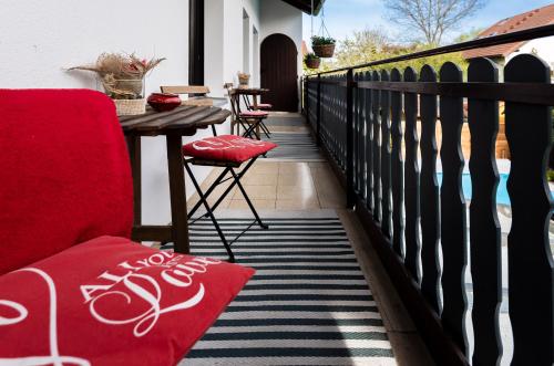a balcony with a red chair and a table at DARFATI 4-Zimmer Wohnung in Pliening