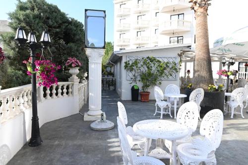 a patio with white tables and chairs and a building at Hotel Onufri in Golem
