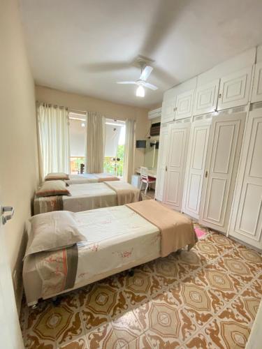 a bedroom with two beds and a closet at Pousada Charitas Inn in Niterói