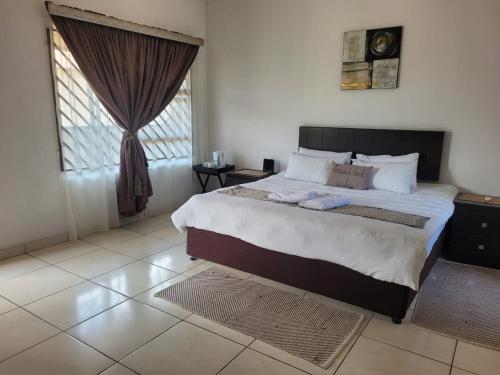 a bedroom with a large bed and a window at Royal Palms Guest Lodge in Newcastle