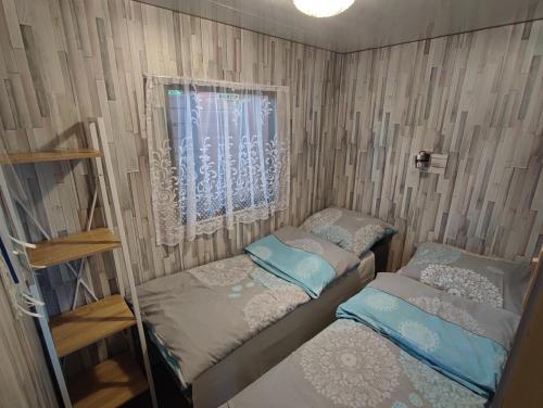 Cette petite chambre comprend 2 lits et une fenêtre. dans l'établissement Siedlisko nr 3 nad jeziorem Skarlińskim, domki letniskowe, mazury, jezioro,bania, à Nowe Miasto Lubawskie