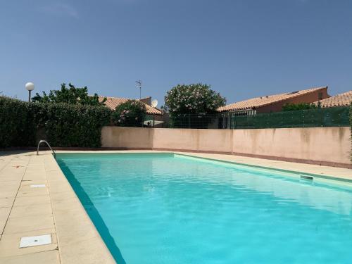 une piscine avec de l'eau bleue devant un immeuble dans l'établissement La Maison Bleue, à Gruissan