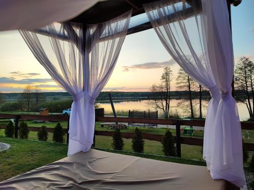 Bett mit einem Fenster mit Flussblick in der Unterkunft Siedlisko nr 4A nad jeziorem Skarlińskim, jezioro, mazury, domki letniskowe in Kurzętnik