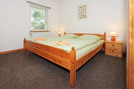 ein Schlafzimmer mit einem großen Holzbett und einem Fenster in der Unterkunft Pension Pradler Wohnung 2 in Carolinensiel