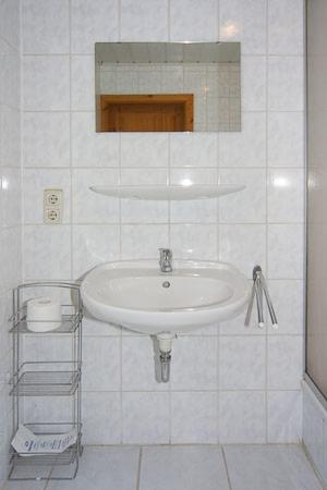 a white bathroom with a sink and a mirror at Pension Pradler Wohnung 2 in Carolinensiel