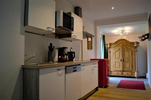 Appartementhaus Sunshine في أخينكيرش: مطبخ فيه دواليب بيضاء وثلاجة حمراء