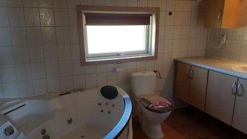 baño con bañera, aseo y ventana en Kalmar 6, en Kägsdorf