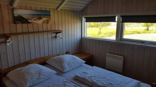 a small bedroom with a bed and two windows at Kalmar 6 in Kägsdorf