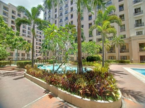 a courtyard with a pool and palm trees in front of a building at Taj's Condotel in Manila