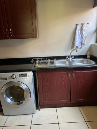 uma cozinha com um lavatório e uma máquina de lavar roupa em Pecanwood Lake View em Hartbeespoort