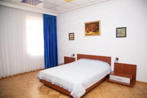 um quarto com uma cama e uma janela com cortinas azuis em SAHIL GARDEN Uzeir Gadgibekova Street em Baku