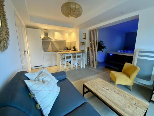 a living room with a blue couch and a table at Le gîte de campagnette avec son jacuzzi privatif in Saint-Martin-Choquel