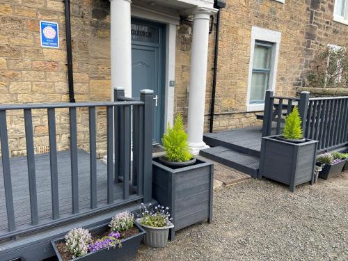 a porch with potted plants in front of a house at The Roxburgh Guest Accommodation in Berwick-Upon-Tweed