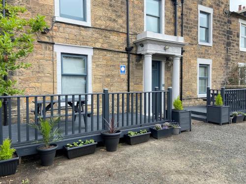 einen Zaun mit Topfpflanzen vor einem Gebäude in der Unterkunft The Roxburgh Guest Accommodation in Berwick-Upon-Tweed