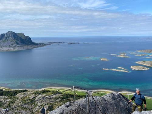 a man standing on top of a mountain overlooking the ocean at Rorsundet Brygge in Vega