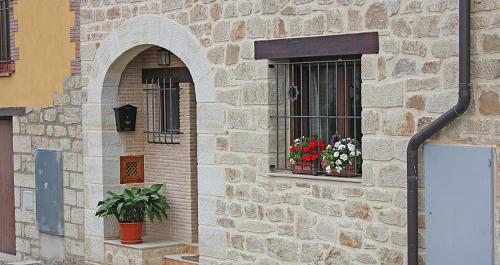 un edificio de ladrillo con dos ventanas con flores. en Rosella de Rubielos, en Fuentes de Rubielos