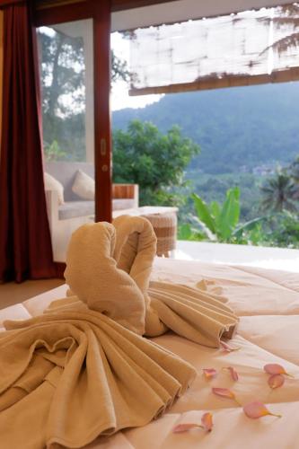 a towel sitting on top of a bed with a window at Abian Dauh Sidemen in Karangasem