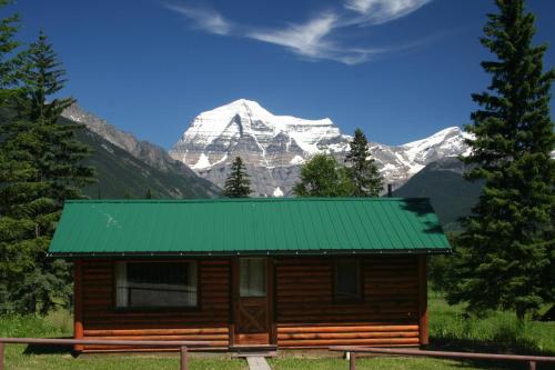 a log cabin with a green roof in front of a mountain at Mount Robson Lodge in Mount Robson