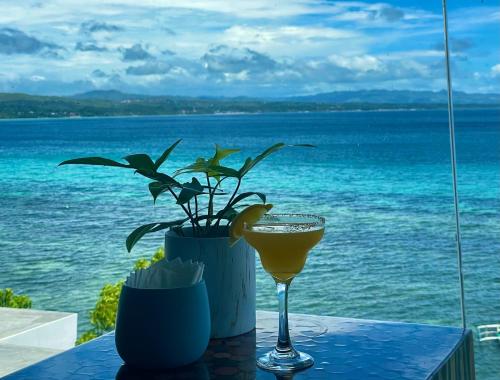 a glass of wine sitting on a table next to the ocean at Epic Suites Bohol ADULTS ONLY in Dauis