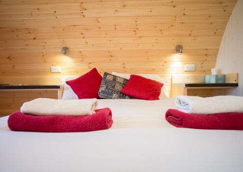 a bed with red and white pillows on it at Hadrian's Holiday Lodges in Greenhead