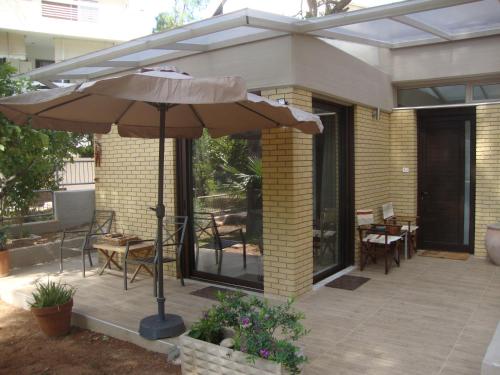 a patio with an umbrella and tables and chairs at Amazing Garden House in Athens