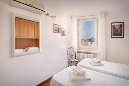 阿尔比萨诺Casa Delle Stelle的一间有两张床和一扇窗户的白色房间
