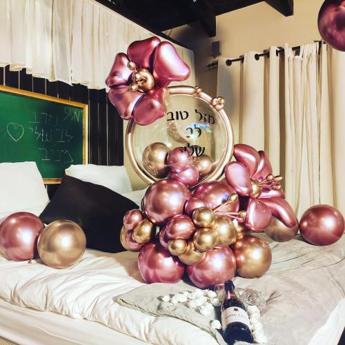 a bunch of balloons on a bed with a clock at Vanilla Grey in Had Nes