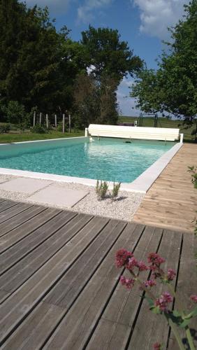 une piscine bleue avec une terrasse en bois et des fleurs dans l'établissement Longère du sud Touraine au Coeur du Val de Loire, à Saint-Jean-Saint-Germain