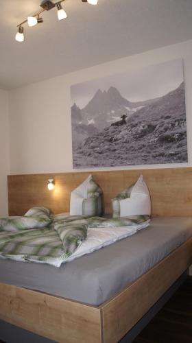 Landhaus Zangerl - Kobelerhof في لاندك: سرير في غرفة مع صورة على الحائط