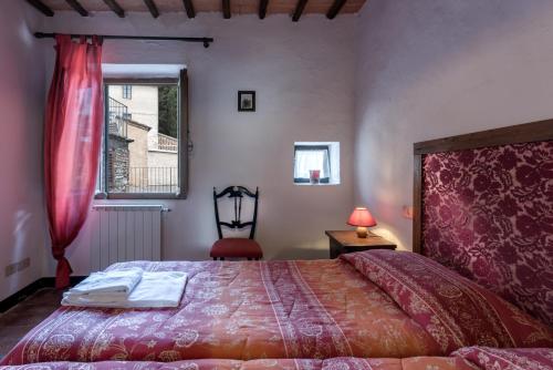 a bedroom with a bed and a chair and a window at Agriturismo Tenuta Di Mensanello in Colle di Val d'Elsa