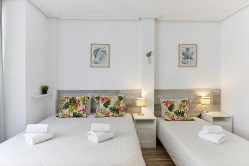 two beds in a room with white walls at Casa SaMARa in Alicante