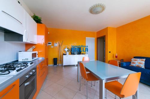 a kitchen with orange walls and a table with orange chairs at Archimede in Lido di Jesolo
