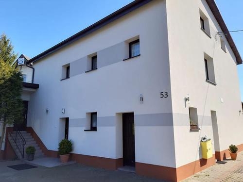 a white building with a black roof at Nella - Pokoje gościnne in Ostrowo