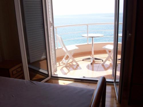 a room with a balcony with a table and chairs at Magic Ionian Apartments & Rooms in Himare