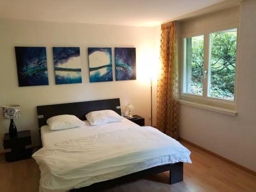 a bedroom with a white bed with three paintings on the wall at Centrally located, Spacious Modern Apartment in Zürich