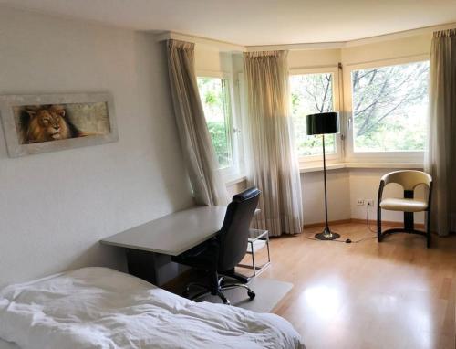 a bedroom with a desk and a bed and windows at Centrally located, Spacious Modern Apartment in Zürich